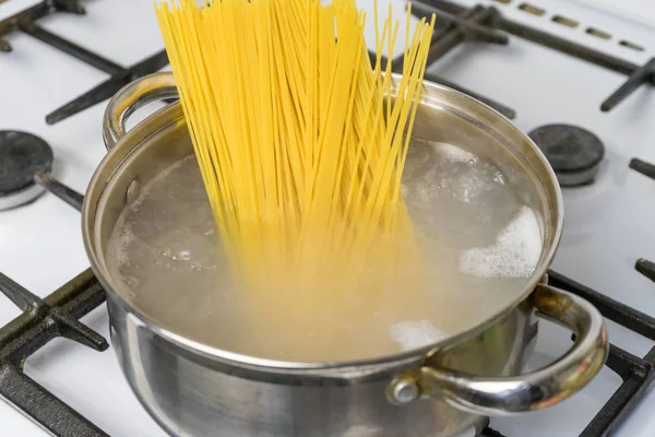 Espaguetis cocidos en agua hirviendo en una estufa de gas. La comida tradicional italiana . — Foto de Stock