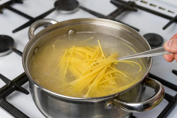 Spageti dimasak dalam air mendidih di atas kompor gas. Makanan tradisional Italia . — Stok Foto