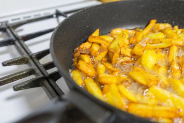 bir gaz sobası üzerinde bir tavada patates kızartma.