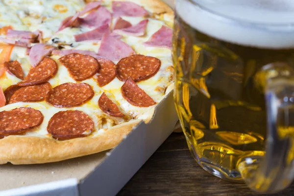Cerveza ligera en vidrio y pizza italiana fragante . — Foto de Stock