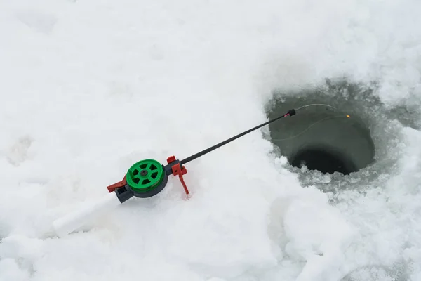 Vara de pesca para pesca de inverno está no gelo. Espere por peixe mordendo na pesca de inverno . — Fotografia de Stock