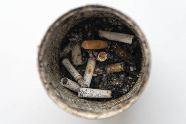 Eski teneke kutu içinde sigara izmaritleri ile. Beyaz bir arka plan resmi.