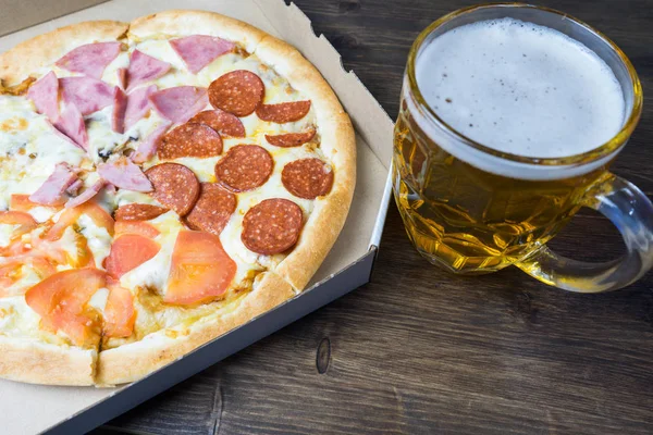 Cerveza ligera en vidrio y pizza italiana fragante . — Foto de Stock