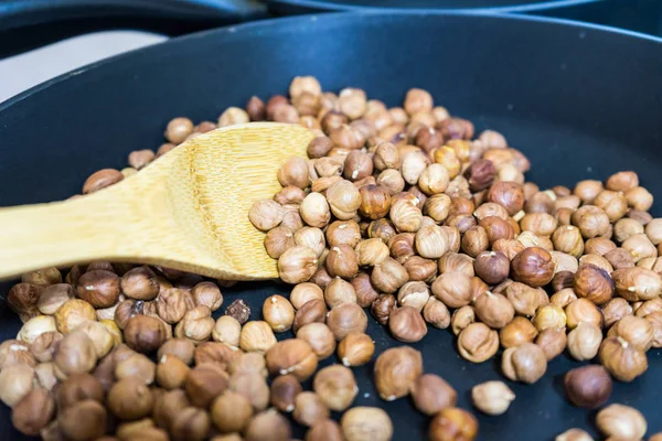 fry hazelnuts in a frying pan. fresh nuts in the pan.