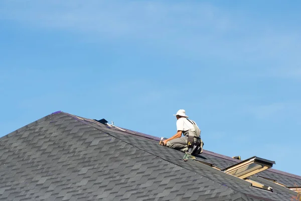 Der Mann auf dem Dach. Foto eines Arbeiters, der das Dach des Hauses repariert. Stockbild