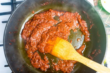 Kızartma tavasında domates sosu pişirmek. Tavada domates sosu pişirmek..