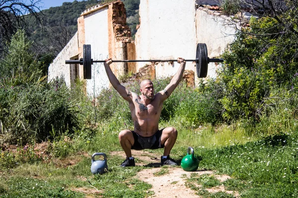 Entrenador sin camisa Deadlifting una barra con dos neumáticos —  Fotos de Stock