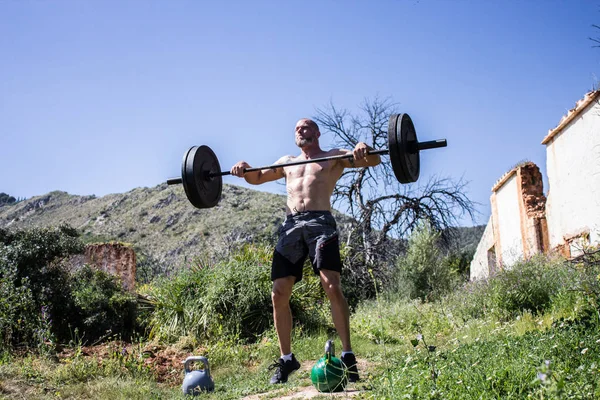 Gömleksiz eğitmen bir halter kapış