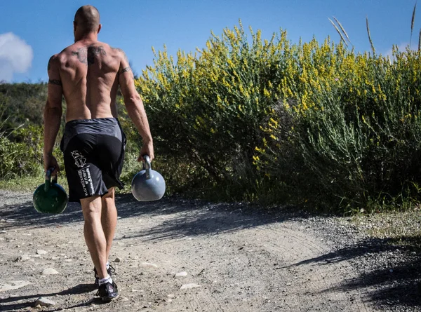 Gömleksiz eğitmen Kettlebell çiftçi yürüyor