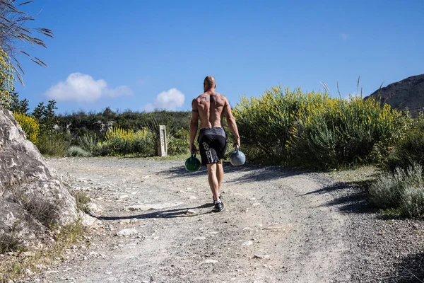 Kettlebell çiftçi gerçekleştirme eğitmen ile iki Kettlebells yürür