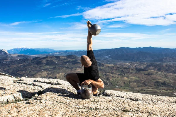 Dağın tepesinde bir kettlebell tutan adam