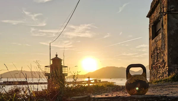 Bir Kettlebell, bir Deniz feneri ve Günbatımı.