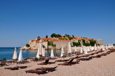 Sveti Stefan Adası bir görünümünü plaj şemsiye ve şezlong, Karadağ ile bir yaz gününde
