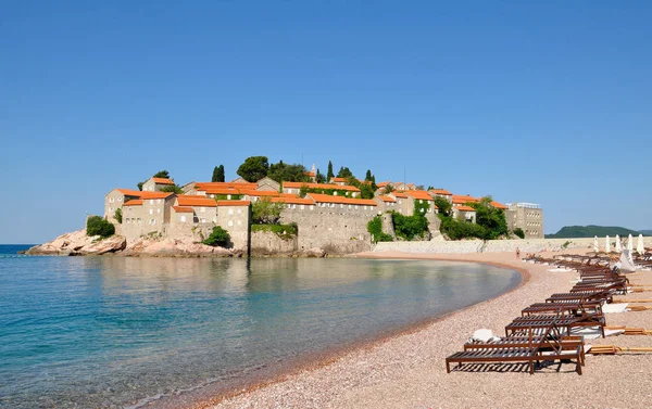 Una vista de la isla de Sveti Stefan en un día de verano con playa y tumbonas, Montenegro — Foto de Stock