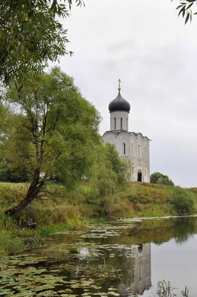 The boy is fishing for the Church of the Intercession on the Nerl with a UNESCO historical monument as part of the Golden Ring of Russia — Stock Photo, Image