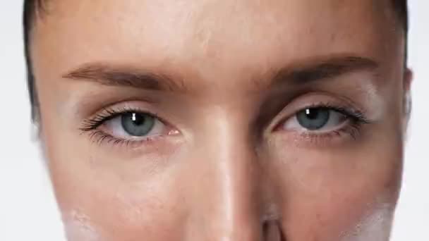 Yeux vue charmante femme regarder caméra gros plan grave sur fond blanc 4K . — Video