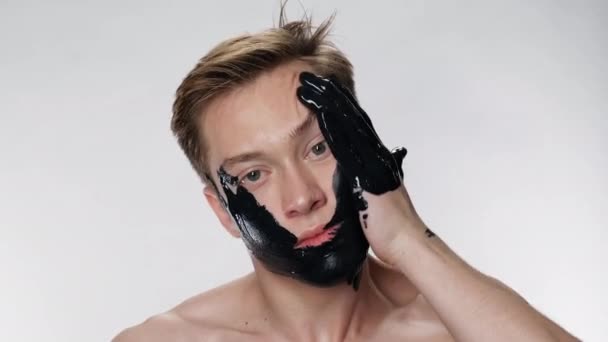 Όμορφος άντρας εφαρμόζει μάσκα προσώπου καλλυντική. Περιβαλλοντική ρύπανση. Μαύρο έλαιο 4k. — Αρχείο Βίντεο