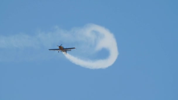 遅い動きのプロペラを持つ飛行機は、ループを示す空の煙パターンを描きます — ストック動画