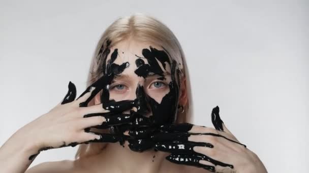 Atrakcyjna dziewczyna stosuje maskę kosmetyczną z bliska. Zanieczyszczenie środowiska. Olej czarny — Wideo stockowe