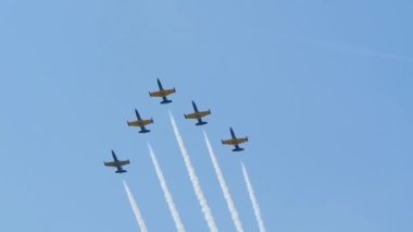 Bir hava gösterisinde beş çapraz jet yavaş çekimde bulutların arasında uçuyor.