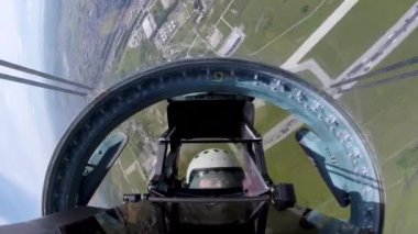 Su-35 uçakları ve sahada dönen ve manevra yapan bir pilot.