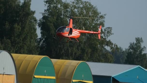 Red helicopter is hanging in the air in slow motion using tail rotor and flying. — Stockvideo