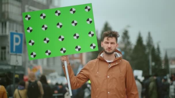 Διαδηλωτής με ένα άδειο πανό στο χέρι σε μια πολιτική συγκέντρωση κοιτάζοντας την κάμερα. — Αρχείο Βίντεο
