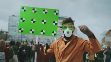 Gaz maskeli isyancı yüzü. Kızgın adam pankartı elinde tutuyor. Gaz maskeli protestocu 4K.