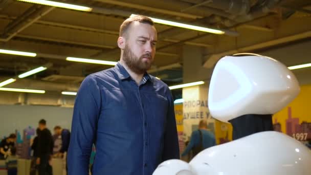 L'uomo guarda robot in attesa di una risposta alla domanda sulla mostra informatica . — Video Stock