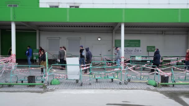 Zamaskowany rynek ludzi w kolejce po koronawirusy. Człowiek czeka w kolejce ulicznej covid-19. — Wideo stockowe