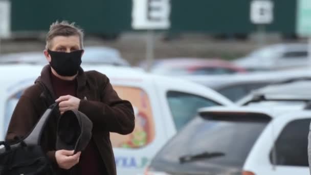 L'uomo in maschera che guarda la telecamera cammina parcheggiato coronavirus. Persone all'aperto covid-19 . — Video Stock