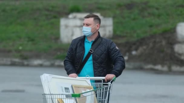 Człowiek twarz maska chodzić wózek naprawa produktu koronawirus. Koszyk z artykułem covid-19 — Wideo stockowe