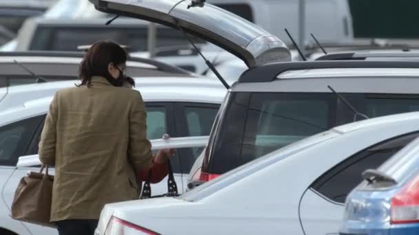 Vrouwen masker stapelen reparatie-item in auto coronavirus. Gemaskerd meisje geparkeerd covid-19. — Stockvideo