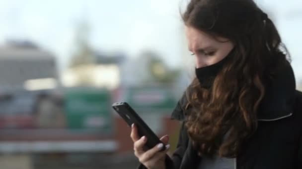 Femme masquée regardant le téléphone sur le virus corona de la rue. Les gens marchent mobile covid-19 . — Video