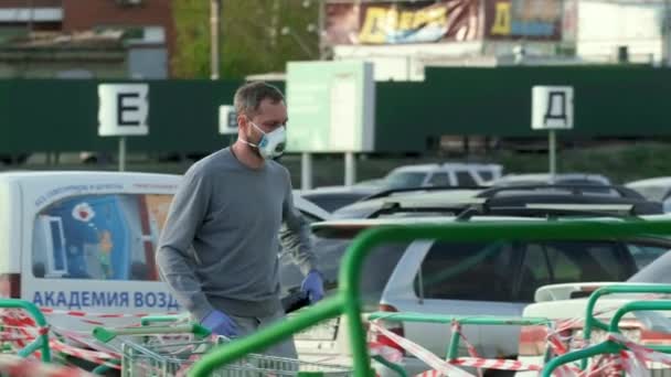 Gemaskerde mensen in handschoenen houden telefoon corona virus vast. Man loopt op geparkeerde covid-19. — Stockvideo