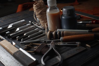 Ahşap arka planda deri el aletleri var. Ayakkabıcıların işyeri. Çalışma masasında el yapımı gizleme ve çalışma araçları