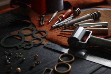 Ahşap arka planda deri el aletleri var. Ayakkabıcıların işyeri. Çalışma masasında el yapımı gizleme ve çalışma araçları