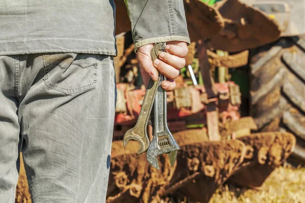 Рабочий с ключами возле трактора — стоковое фото
