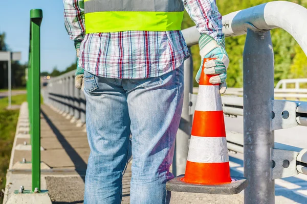 Trabalhador da construção de estradas com cone de tráfego perto da estrada — Fotografia de Stock
