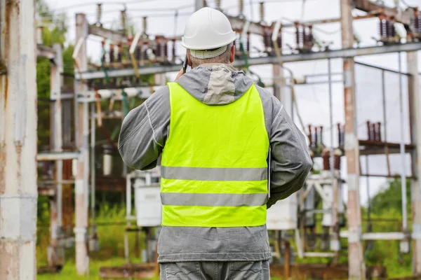 Electrician talking on the phone in electrical substation — Stock Photo, Image