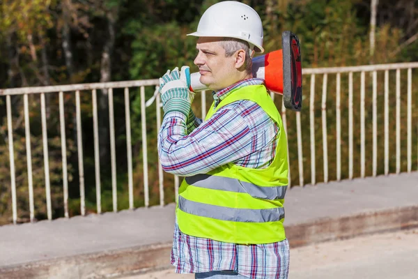 Trabajador de la construcción de carreteras con cono de tráfico en el puente —  Fotos de Stock