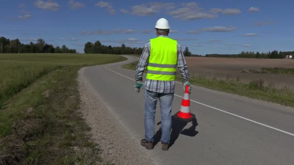 Lucrător în construcții rutiere cu con de trafic pe drum — Videoclip de stoc