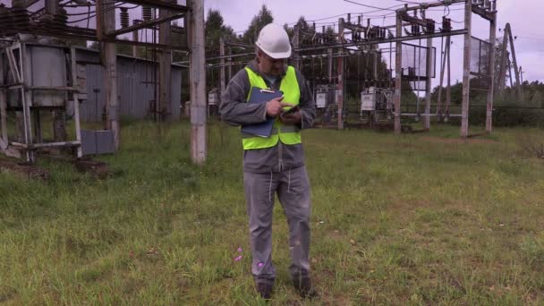 Инженер-электрик дает задание подстричь траву на подстанции — стоковое видео