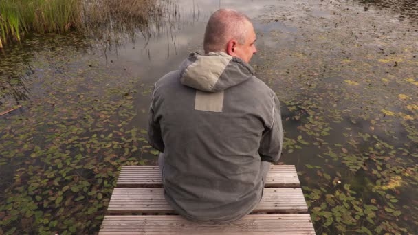O homem com a flor na passarela no lago — Vídeo de Stock