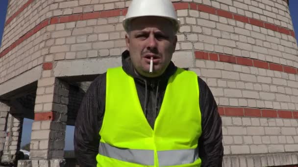 Worker with cigarette in mouth look to camera and touching eye — Stock video