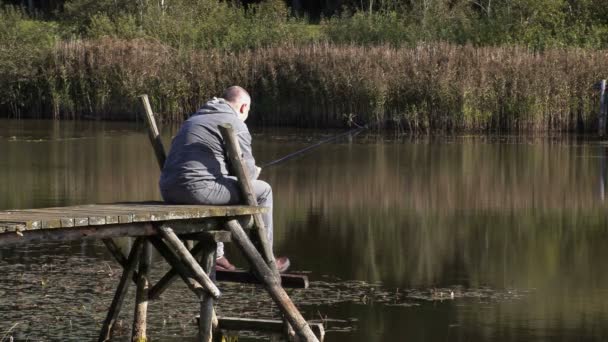 Man sitting on footbridge and fishing — Stock Video