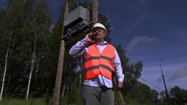 Yüksek gerilim hatları ve trafo yakınındaki telefonda konuşurken elektrikçi 