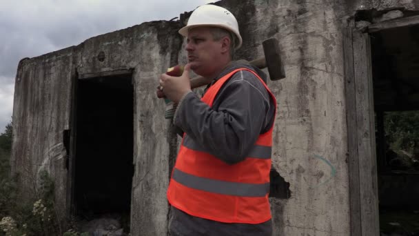 Trabalhador com martelo no ombro come maçã — Vídeo de Stock