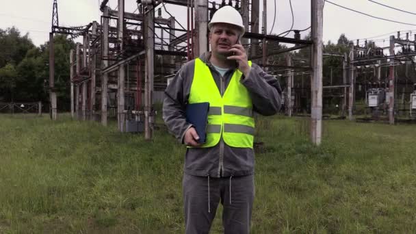Elektricien ingenieur praten aan de telefoon bij onderstation — Stockvideo