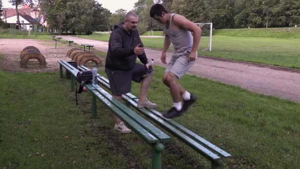 Joven atleta hacer ejercicios para las piernas cerca de entrenador en el estadio — Vídeos de Stock